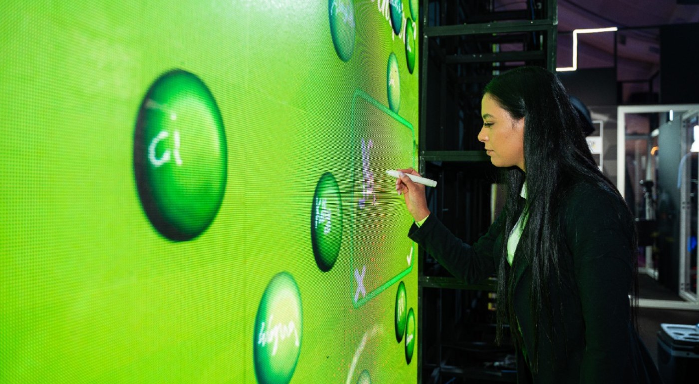 Participante interagindo por toque em um painel durante um evento